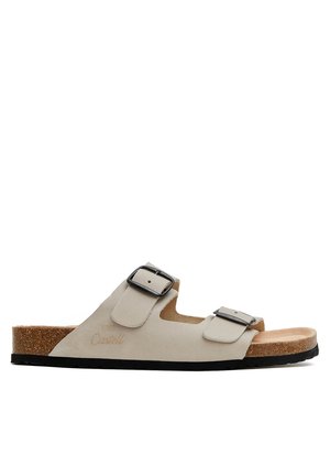 Sandalia beige de punta abierta con dos hebillas negras ajustables, plantilla de corcho y suela negra texturizada, vista lateral.