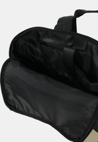 Interno di uno zaino nero che mostra il compartimento imbottito per laptop e le tasche organizer con una cerniera parzialmente aperta e il manico superiore.