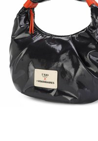 Zwarte glanzende handtas met een geknoopte oranje handgreep. Heeft een crème label aan de zijkant met de tekst "UNIO X LES VISIONNAIRES". Zachte, afgeronde vorm.