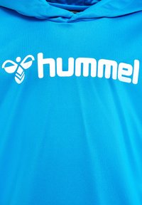 Blauer Kapuzenpullover aus leichtem Material mit einem großen weißen "hummel"-Logo und einem auffälligen Bienenemblem über dem Schriftzug.