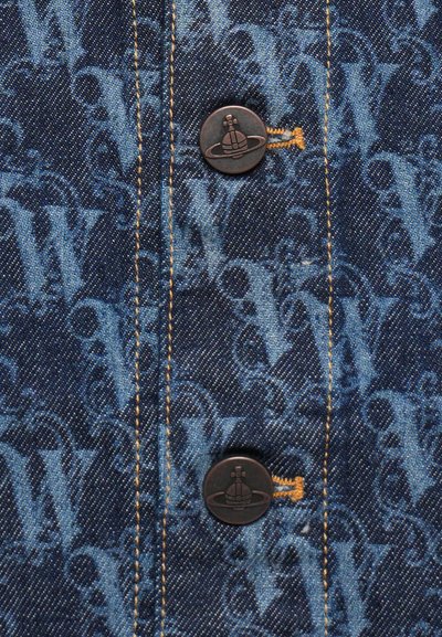 Denimstoff mit einem blauen, tonal gehaltenen Monogrammmuster. Zwei dunkle Knöpfe mit einem Logo und gelben Nähten, die entlang der Naht sichtbar sind.