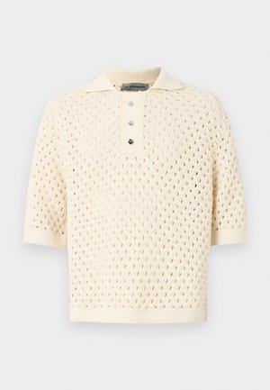 Polo a maniche corte color crema con un design a maglia aperta e testurizzata. Presenta un colletto e una chiusura a tre bottoni. Tessuto morbido e traspirante.