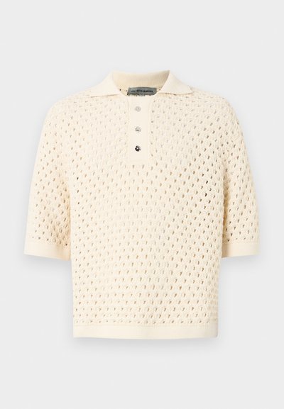 Polo à manches courtes en crème avec un design en tricot ouvert texturé. Doté d'un col et d'une fermeture à trois boutons. Tissu doux et respirant.