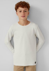 Witte langemouwen shirt gemaakt van een zachte stof, met een ronde halslijn en een klein zwart logo-label aan de zoom.