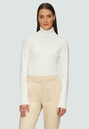 Weißes Turtleneck-Oberteil mit langen Ärmeln, glatte Textur, figurbetontes Design. Kombiniert mit beigen High-Waist-Hosen, minimalistischer Stil.