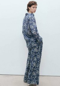Set di camicia e pantaloni a fantasia paisley blu e bianco, caratterizzato da una vestibilità morbida e maniche lunghe. Realizzato in un tessuto leggero con una leggera lucentezza.