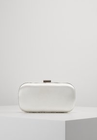 Rektangulär metallisk silverfärgad clutchväska med en slät yta, prydd med en pärlbesättning och ett lås på toppen.