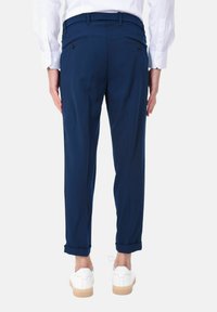 Pantaloni blu navy con vestibilità sartoriale, dotati di due tasche posteriori con bottoni, orli risvoltati e una texture del tessuto liscia.