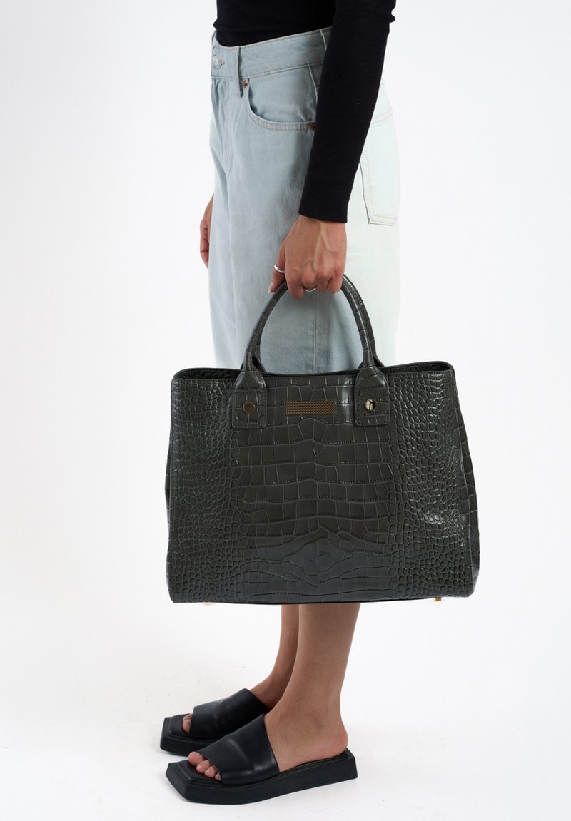 Sac à main en cuir vert foncé avec texture crocodile, de forme rectangulaire, avec deux poignées, quincaillerie en ton doré et finition lisse et brillante.