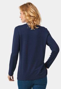 Marineblaue Langarmbluse aus weichem Stoff, mit rundem Halsausschnitt und lockerer Passform, mit feinen Nähten entlang der Nähte.