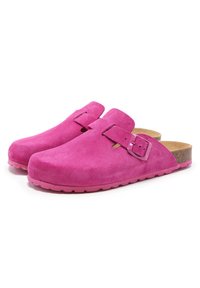 Sabots en suède rose avec une finition lisse, une sangle à boucle réglable, une semelle intérieure en liège et une semelle en caoutchouc présentant un motif en vagues.