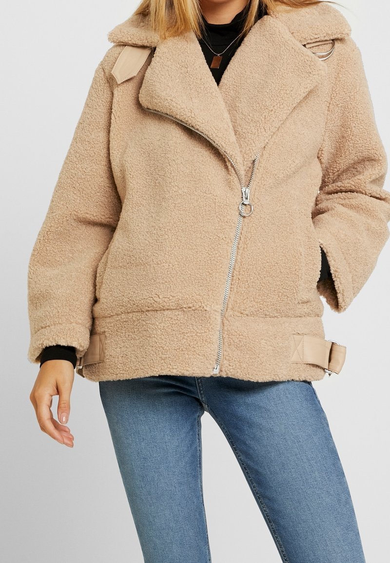 Beige faux fur jakke med lynlås foran, bred krave og sidestraps. Har en struktureret stofkvalitet og en afslappet pasform, perfekt til lag-på-lag.