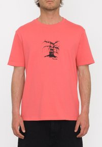 T-shirt coral à manches courtes en coton, avec un graphique d'arbre noir au centre, coupe décontractée, col rond.