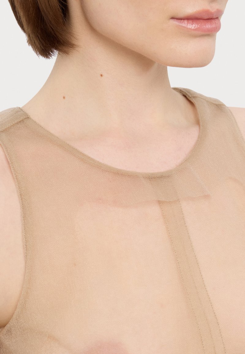 Simpelt beige stoftop med rund halsudskæring, der har fine søm og en subtil gennemsigtig tekstur. Ingen synlige mønstre eller detaljer.