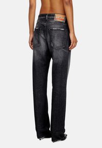 Zwarte denim jeans met een relaxte pasvorm, vervaagde was, en contrasterende stiksels; heeft twee achterzakken en een label op de tailleband.