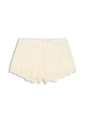 Shorts beige pour femmes, bordés de dentelle avec des bords festonnés et un petit nœud noué à la taille élastique sur fond blanc.
