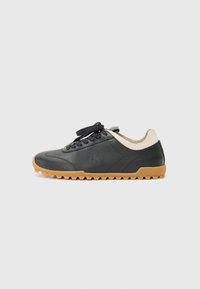 Sneaker in pelle nera con suola in gomma color caramello, punta tonda e design con lacci. Presenta un accento sul tallone beige e un logo in rilievo sul lato.