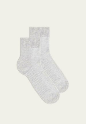Calze di cotone grigio chiaro con polsini a coste, texture morbida, lunghezza fino al polpaccio e design minimalista, che mostrano un sottile motivo mélange.