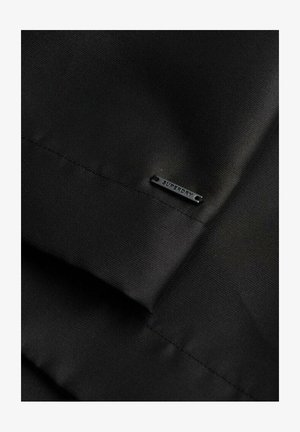 Schwarzer Stoff mit einer glatten Textur, versehen mit einem kleinen schwarzen "SUPERDRY"-Tag, der ein sauberes und einfaches Design zeigt.