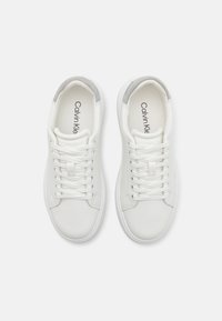 Valkoiset nahkakengät, joissa on sileä pinta, harmaat kivennäiskangaskorostukset kannassa, sekä valkoiset nauhat. Ominaisuuksiin kuuluu minimalistinen muotoilu ja pyöreä varvas.