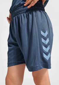 Marineblaue Sportshorts mit elastischem Bund, vertikalen Nadelstreifen und einem hellblauen Chevron-Design auf der linken Seite.