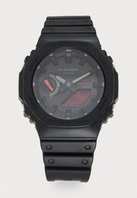 Montre G-Shock avec boîtier en plastique noir et bracelet, affichage analogique-numérique, fonction solaire, accent rouge sur le sous-cadran, design robuste.