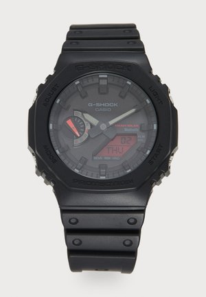 G-Shock watch with black plastic case and strap, analog-digital display, solar power feature, red accent on sub-dial, rugged design.