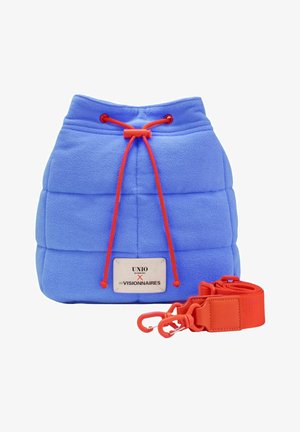 Sac seau matelassé bleu avec fermeture à cordon rouge et bandoulière rouge amovible, avec une étiquette blanche avec texte noir.