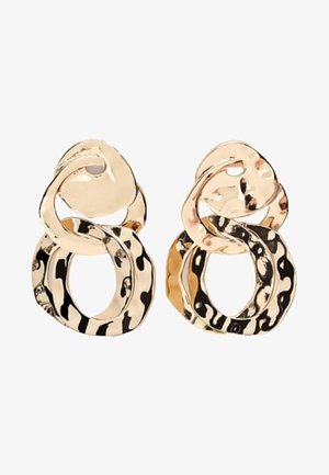 Boucles d'oreilles en métal doré avec deux formes ovales irrégulières entrelacées, la grande ovale inférieure présentant un motif martelé et texturé.