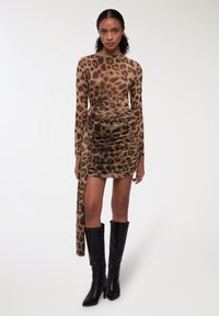 Abito a maniche lunghe con stampa leopardata, dettagli arricciati e fiocco laterale; abbinato a stivali neri con tacco al ginocchio. Texture liscia.