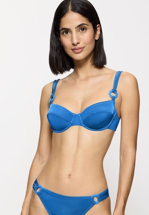 Blauer Bikini-Oberteil mit Unterdraht, geformten Cups und dünnen verstellbaren Trägern, mit runden Akzenten aus Metall. Das Material wirkt glatt und glänzend.