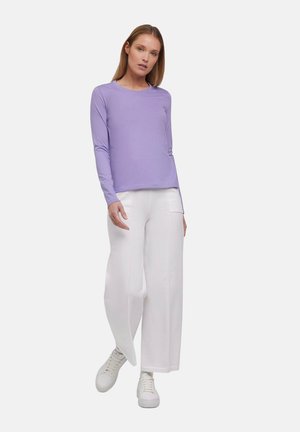Lichtpaarse lange mouwen shirt met een ronde hals, gecombineerd met brede witte broeken en witte sneakers, wat zorgt voor een ontspannen outfit.