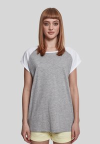 Grå kortærmet t-shirt med hvide raglanærmer, rund halsudskæring og blød tekstur. Kombineret med lysegule shorts.