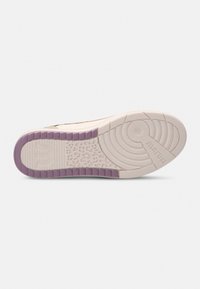 Shoe sole with a textured white surface, features a purple accent along the edge, circular patterns, and raised branding.