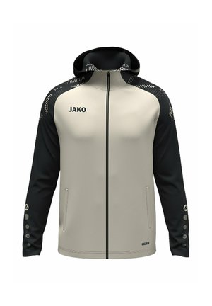 Chaqueta deportiva con capucha en beige claro y negro, cierre delantero, logo JAKO en el pecho y detalles estampados en los hombros y mangas.