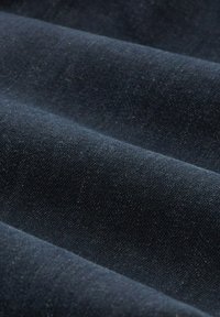 Tejido de color azul oscuro con una textura suave, que presenta un sutil patrón de tejido. El material parece blando y flexible, doblado en múltiples capas.
