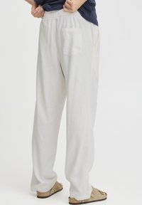 Lyse linnedbukser med løs pasform, elastisk taljebånd og baglomme. Bruges med brune sandaler.