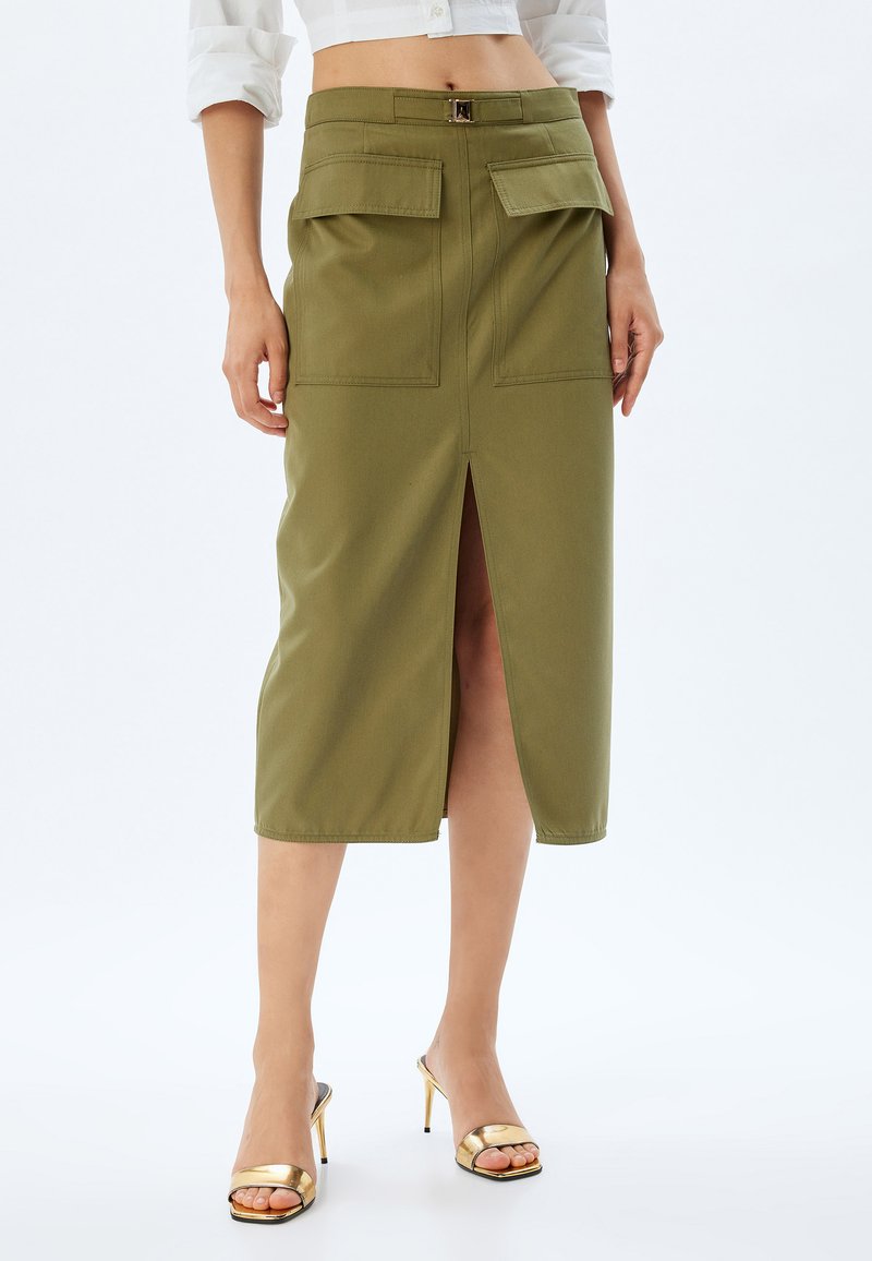 Falda midi de algodón en verde oliva con una abertura frontal, dos bolsillos superiores y un detalle de cinturón en la cintura. Textura suave, diseño clásico.
