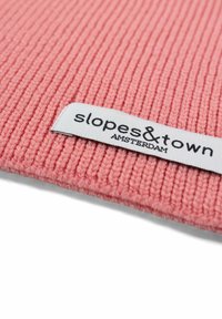 Roze ribbelstof met een gladde textuur, met een wit label waarop staat "slopes & town AMSTERDAM."