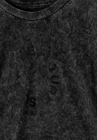 Tela texturada de color gris carbón con un texto circular en relieve sutil que dice "NO WITH THE FUTURE IS" y pequeños caracteres japoneses debajo.