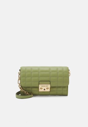 Sac bandoulière en cuir matelassé vert avec bandoulière chaîne dorée et fermoir doré avec l’étiquette Michael Kors sur un fond uni.