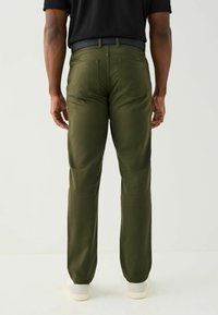 Zelené kalhoty z hladké látky, s klasickým rovný střihem, dvěma zadními kapsami a kontrastním páskem s poutkem.