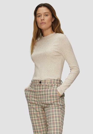 Hellbeige Langarmshirt mit gesprenkelter Textur, kombiniert mit karierter, hoch taillierter Hose in Creme, Marineblau, Rot und Grüntönen.