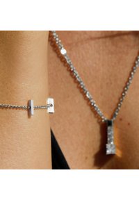 Silberne Halskette und Armband mit geometrischem Anhänger. Die Kette ist fein verlinkt und besitzt reflektierende Oberflächen sowie ein minimalistisches Design, das die Eleganz unterstreicht.