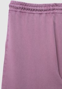 Lila Jogginghose mit elastischem Bund, glatter Textur und minimalistischem Design. Verfügt über Seitentaschen und einen bequemen Sitz.