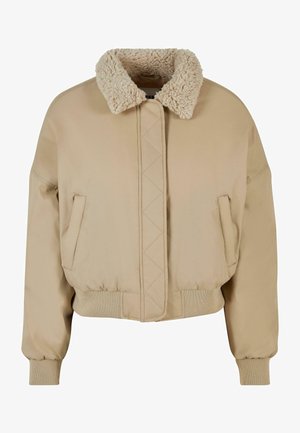 Beige cropped jacket with a fluffy collar, featuring a front closure, side pockets, and ribbed cuffs and hem. Soft fabric with a smooth texture.