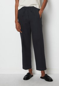 Dark gray, loose-fitting trousers with an elastic waistband and drawstring. Features side pockets and a cropped, straight leg design.