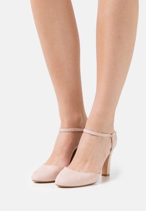 Blush pink suede high-heeled shoes with a pointed toe, an ankle strap, and a gold buckle detail, featuring a smooth texture and slim heel.