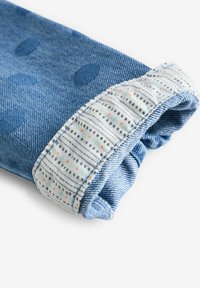 Manches en denim avec des pois bleus ; le poignet présente un tissu à motifs avec des lignes et de petits points dans des couleurs pastel ; texture douce, bord roulé.
