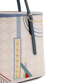Borsa tote realizzata in materiale beige trapuntato con motivi geometrici colorati. Presenta un manico blu scuro e dettagli in oro.